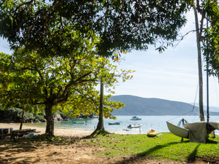 A Praia da Aroeira possui areia parcialmente sombreada, com árvores e palmeiras