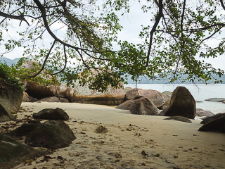 O lado direito da praia possui pedras de diferentes tamanhos e formatos